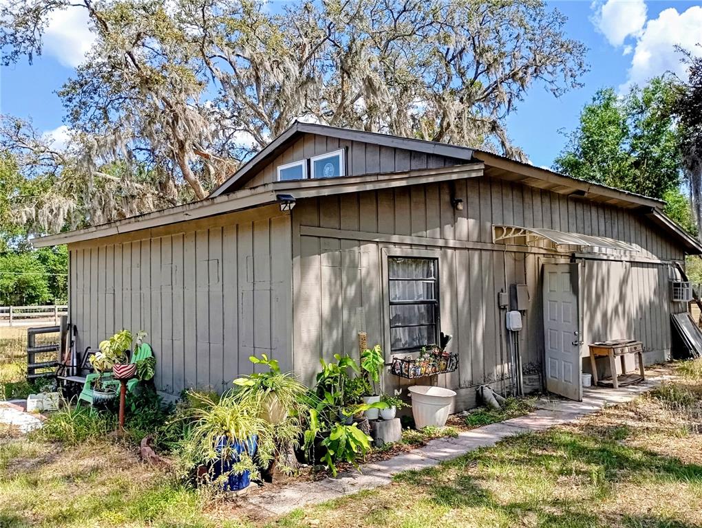 A brown, single-story exterior structure with vertical siding, a metal door, and potted plants — 3607 RANCH ROAD, VALRICO, FL