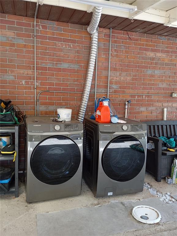 Two Samsung laundry appliances sit against a brick wall under a covered outdoor area — 3607 RANCH ROAD, VALRICO, FL