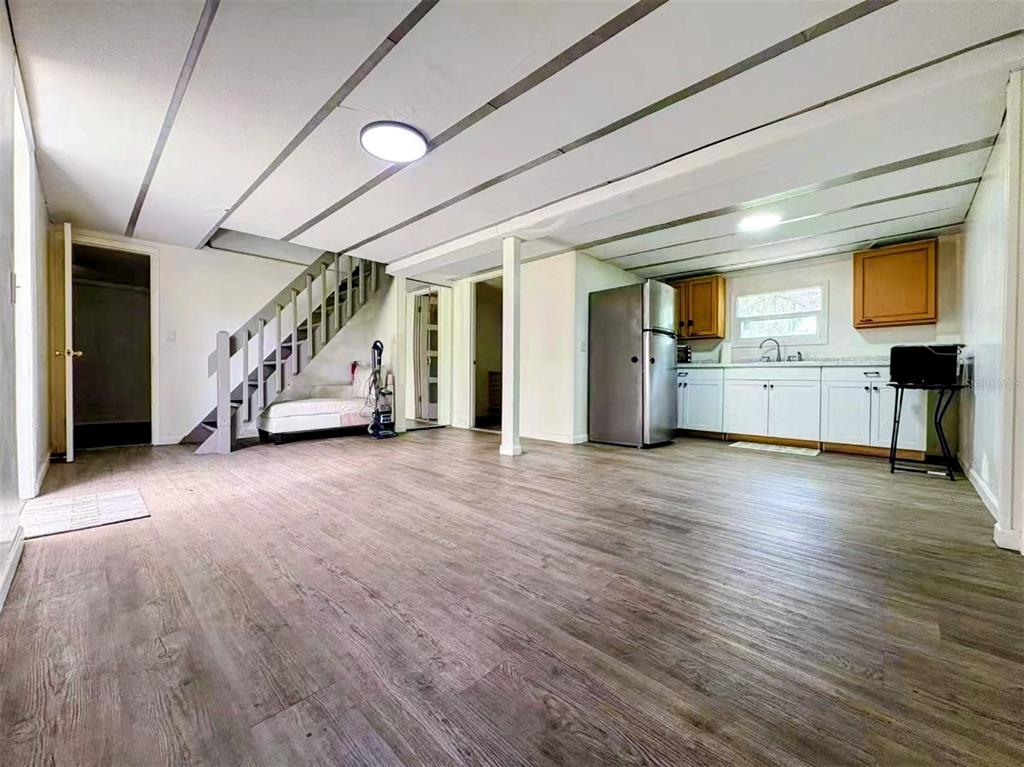 An open-concept room features wood-look flooring, a staircase, and a kitchen with white cabinets — 3607 RANCH ROAD, VALRICO, FL