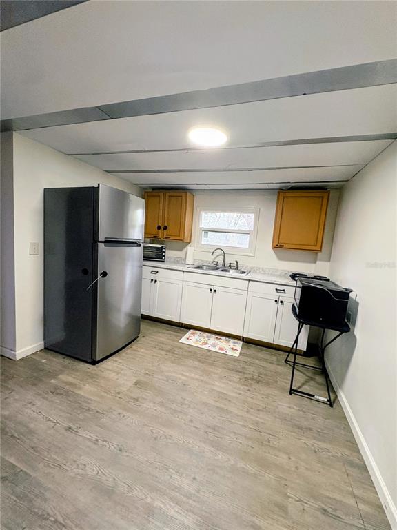 A kitchen features white lower cabinets, wood upper cabinets, a stainless steel refrigerator, and flooring — 3607 RANCH ROAD, VALRICO, FL