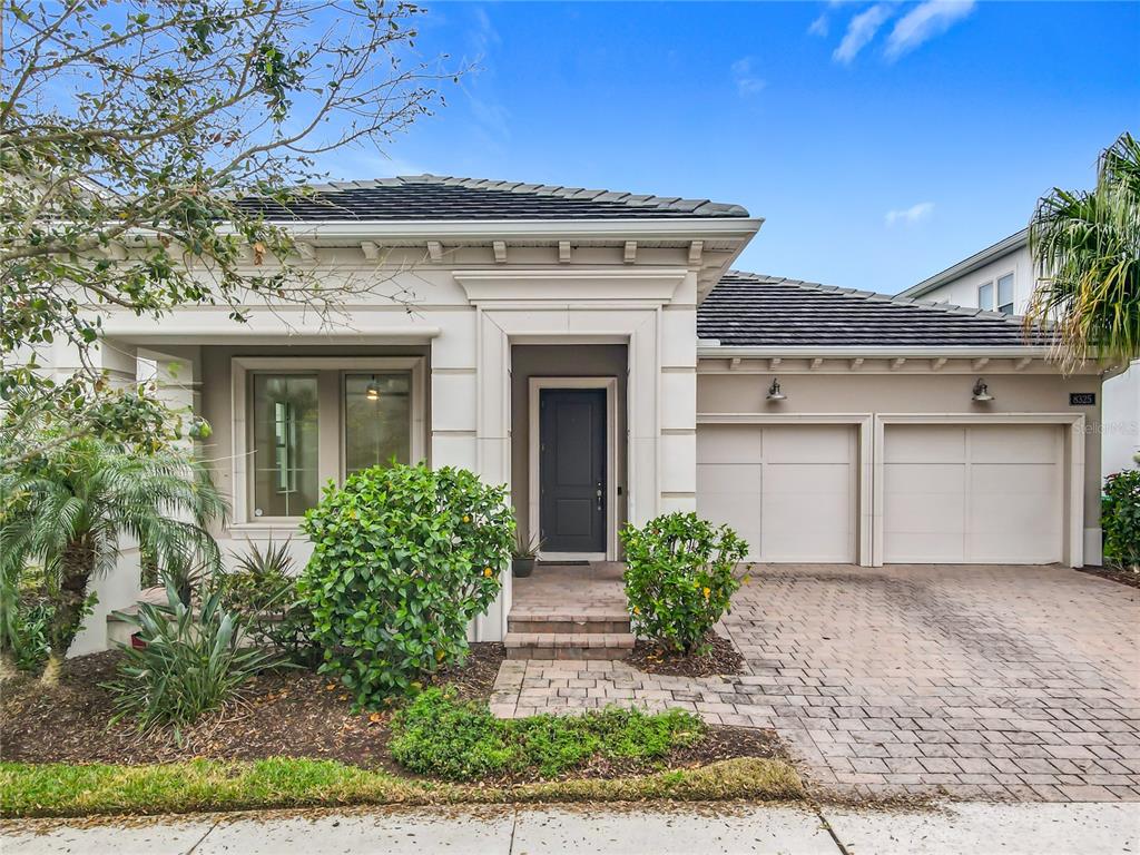 A single-story house with a dark front door, two-car garage, and a paved driveway — 8325 TOPSAIL PLACE, WINTER GARDEN, FL
