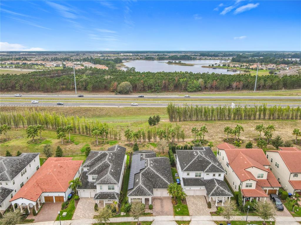 An aerial view shows a row of suburban houses situated near a highway and lake — 8325 TOPSAIL PLACE, WINTER GARDEN, FL
