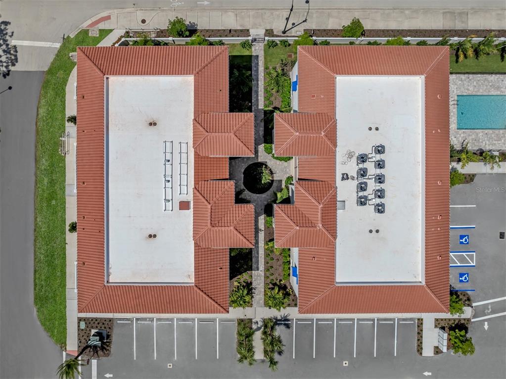A swimming pool sits in front of a three-story apartment building with blue awnings — 787 S. TAMIAMI TRAIL UNIT 302, VENICE, FL
