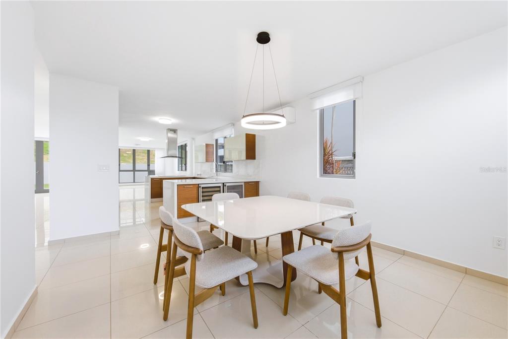 A modern dining area with a white table and chairs sits adjacent to a kitchen — 70 CALLE AQUAMARINA, SAN JUAN, PR