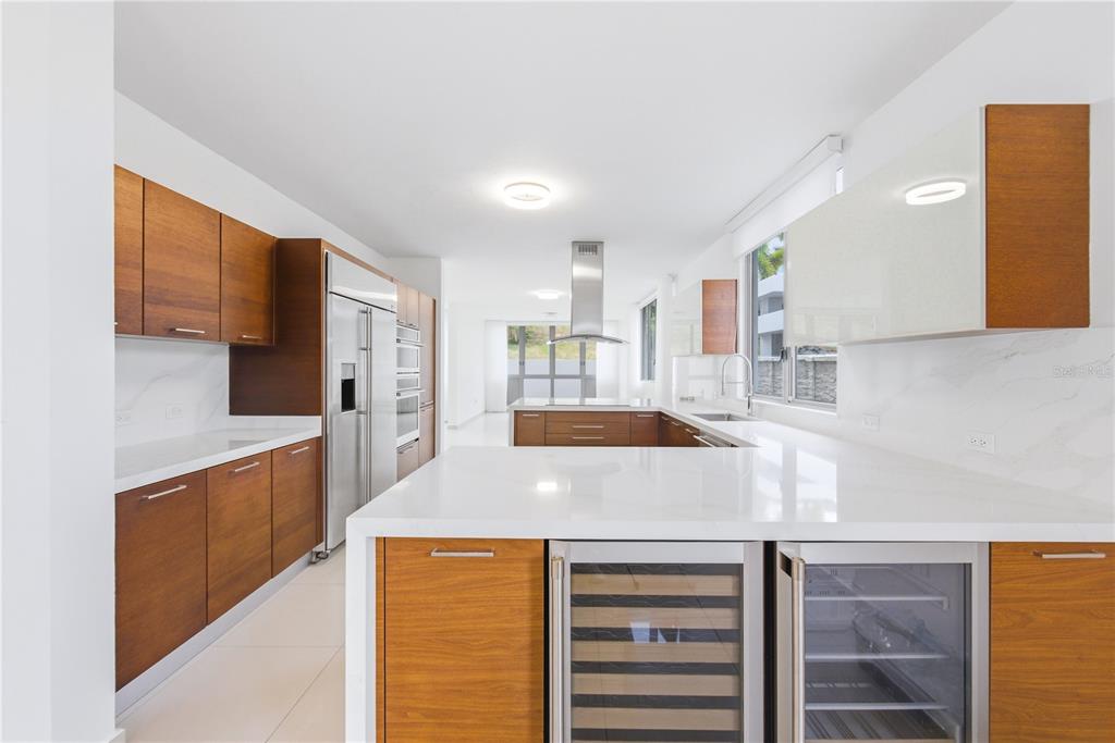 A modern kitchen features wood cabinets, white countertops, stainless steel appliances, and a wine cooler — 70 CALLE AQUAMARINA, SAN JUAN, PR