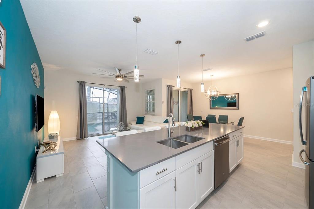 A modern kitchen island with gray countertops overlooks an open-concept living and dining area — 4830 DEDICATION STREET, KISSIMMEE, FL