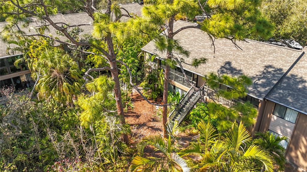 An elevated view of a multi-story apartment building surrounded by lush trees and vegetation — 1717 PELICAN COVE ROAD UNIT GL434, SARASOTA, FL