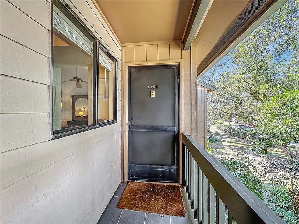 A view of an apartment entrance with a screen door, window, and outdoor walkway — 1717 PELICAN COVE ROAD UNIT GL434, SARASOTA, FL