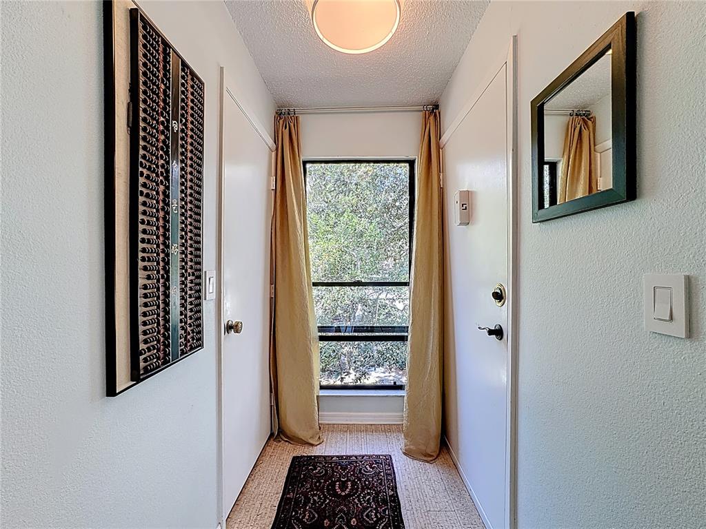 A narrow hallway features a window with gold curtains, a rug, and wall-mounted decor — 1717 PELICAN COVE ROAD UNIT GL434, SARASOTA, FL