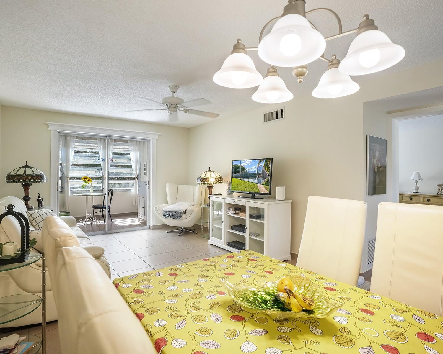 A dining area with a patterned tablecloth opens into a living room with tiled floors — 2615 NE 3rd Court # 314, Boynton Beach FL 33435, BOYNTON BEACH, FL