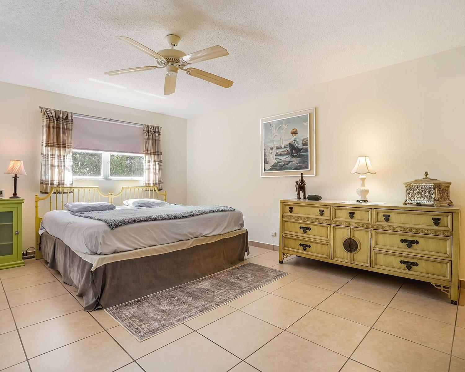 A bedroom with tile flooring, a ceiling fan, a bed, and a long wooden dresser — 2615 NE 3rd Court # 314, Boynton Beach FL 33435, BOYNTON BEACH, FL
