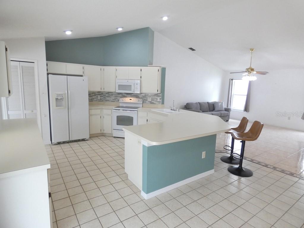 A kitchen with white cabinets, a teal accent wall, and a breakfast bar island — 907 BRITTANY PARK BOULEVARD, TARPON SPRINGS, FL