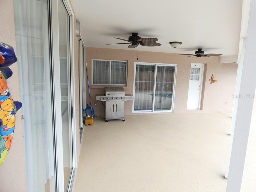 A covered patio features a stainless steel grill, two ceiling fans, and sliding glass doors — 907 BRITTANY PARK BOULEVARD, TARPON SPRINGS, FL
