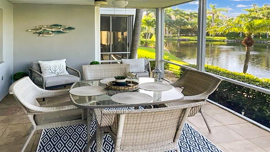 A screened-in patio features a glass-topped dining table, wicker chairs, and a view of water — 1230 SIESTA BAYSIDE DRIVE UNIT 1230-D, SARASOTA, FL