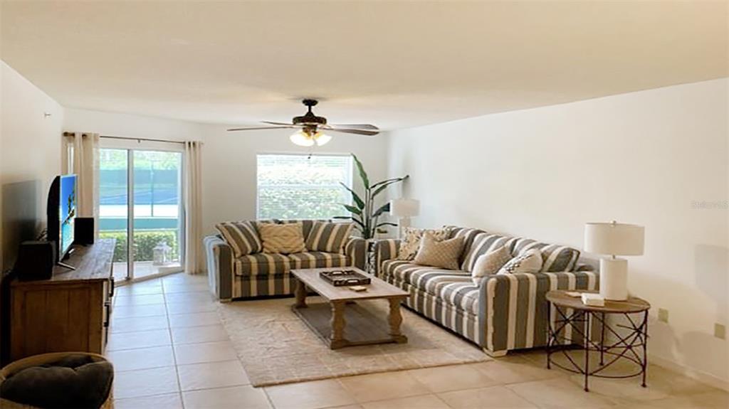 A living room features striped sofas, a wooden coffee table, and a sliding glass door — 1230 SIESTA BAYSIDE DRIVE UNIT 1230-D, SARASOTA, FL