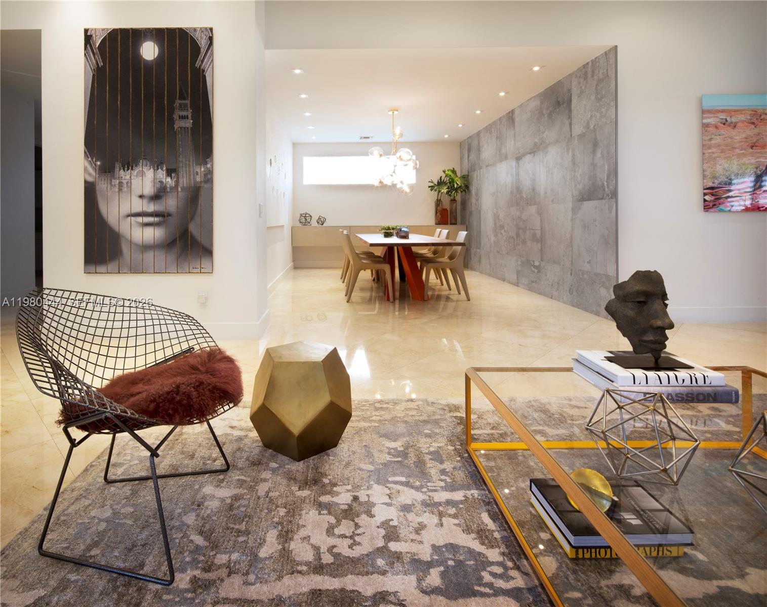 A modern living and dining area features a wire chair, glass coffee table, and tiled wall — 1651 NE 196th St, Miami FL 33179, MIAMI, FL