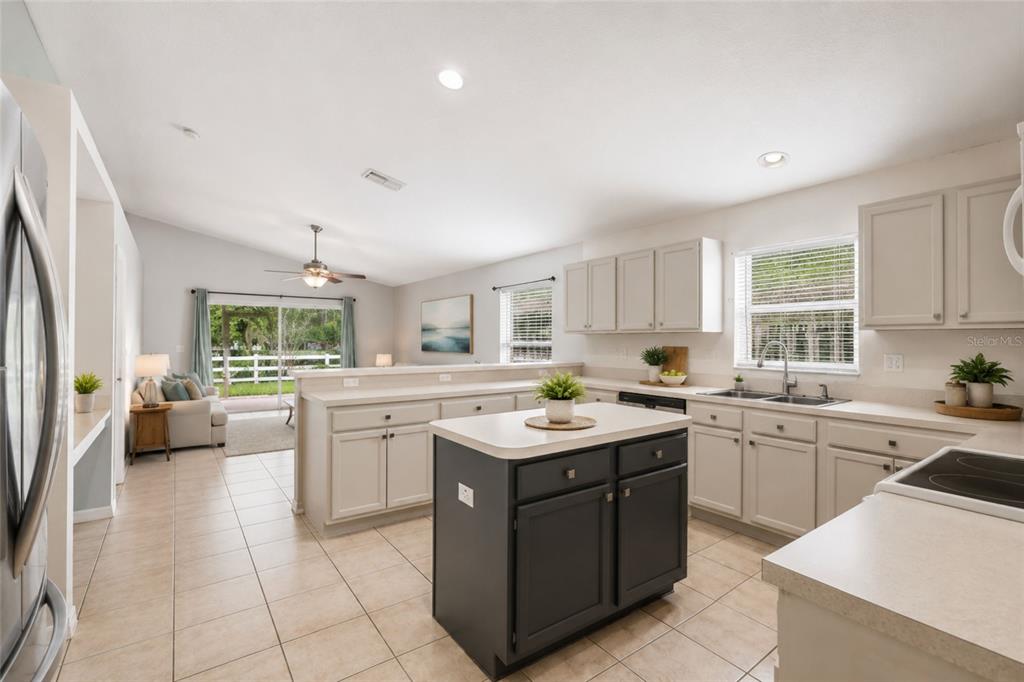 A kitchen with light cabinets, a dark island, and a view into the living area — 3002 LORIMER CT, GROVELAND, FL