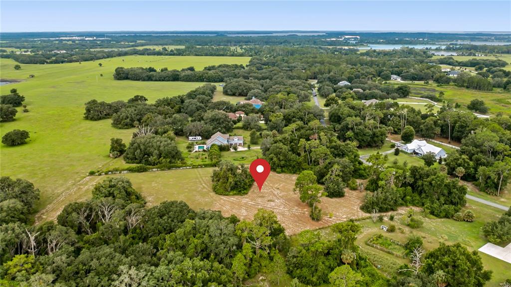 An aerial view shows a cleared lot surrounded by trees and nearby residential houses — TROTTING HORSE LANE, TAVARES, FL