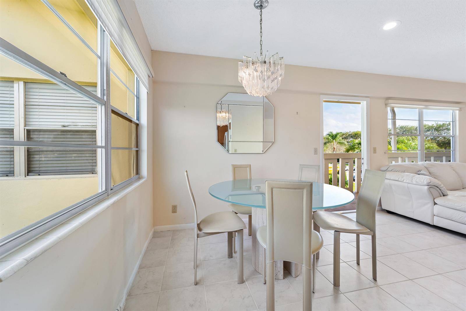 A dining area features a glass-topped table, four chairs, a chandelier, and a balcony door — 200 Dorset E, Boca Raton FL 33434, BOCA RATON, FL