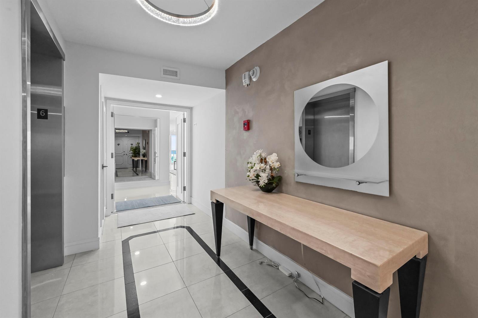 A modern hallway features a console table, a circular mirror, and an elevator entrance — 2800 S Ocean Boulevard # A, Boca Raton FL 33432, BOCA RATON, FL