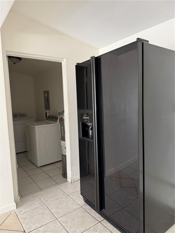 A black refrigerator stands next to a doorway leading to a laundry room with appliances — 4737 56TH AVENUE N, ST PETERSBURG, FL