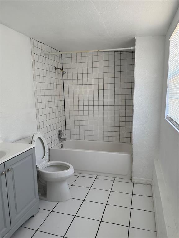 A bathroom features a white tiled shower-tub combo, a toilet, and a grey vanity cabinet — 4737 56TH AVENUE N, ST PETERSBURG, FL