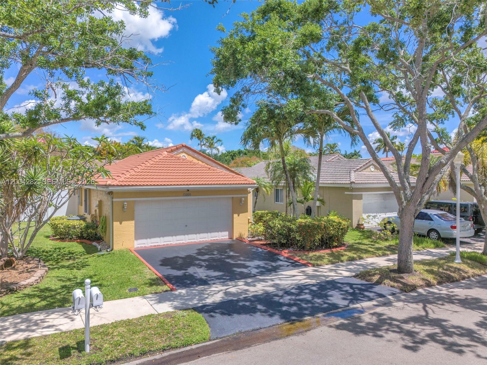 A single-story house with a terracotta roof, a two-car garage, and a paved driveway — 1600 Salerno Cir, Weston FL 33327, WESTON, FL