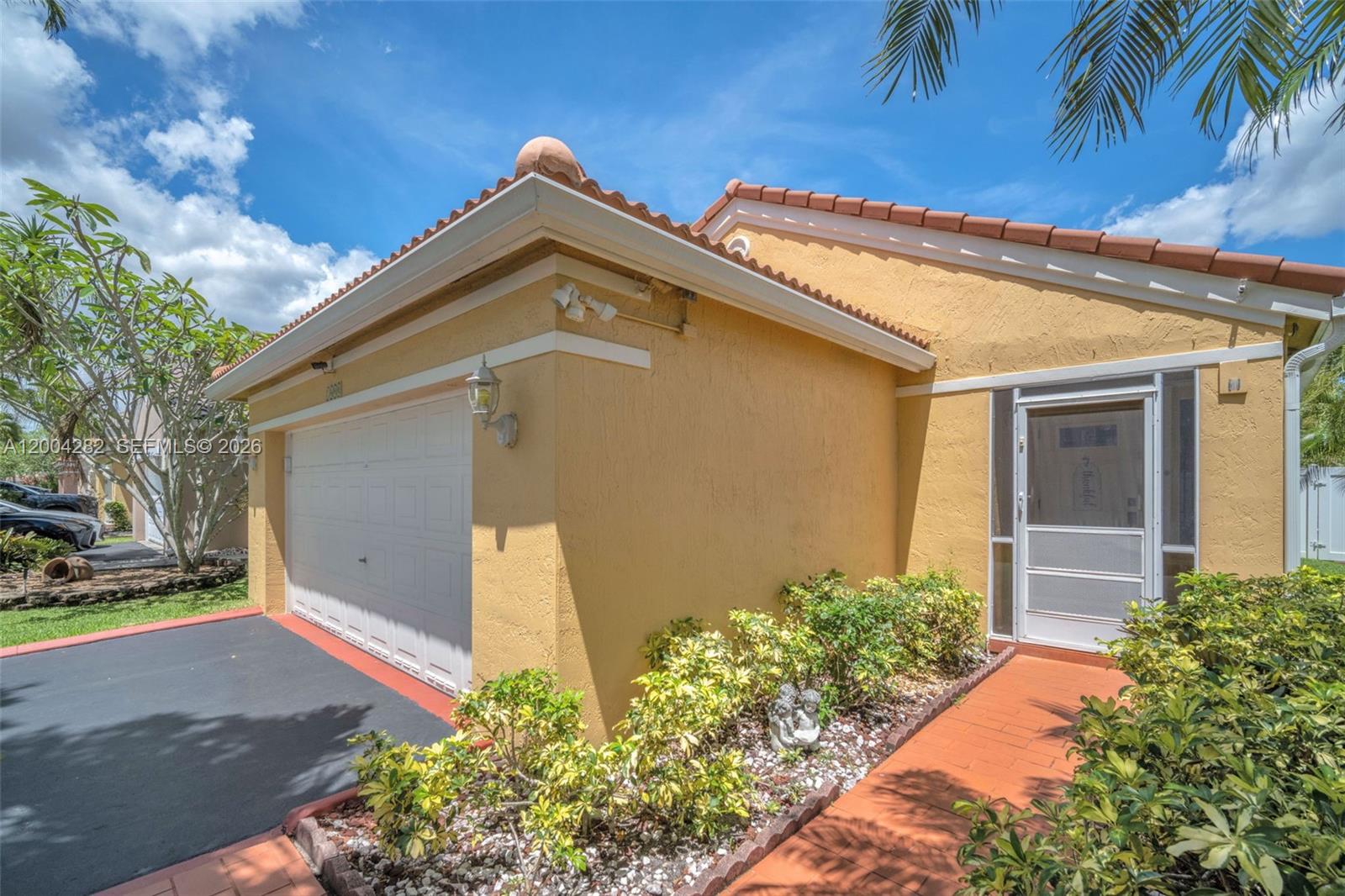 A yellow stucco house with a tiled roof, garage, and a brick walkway — 1600 Salerno Cir, Weston FL 33327, WESTON, FL