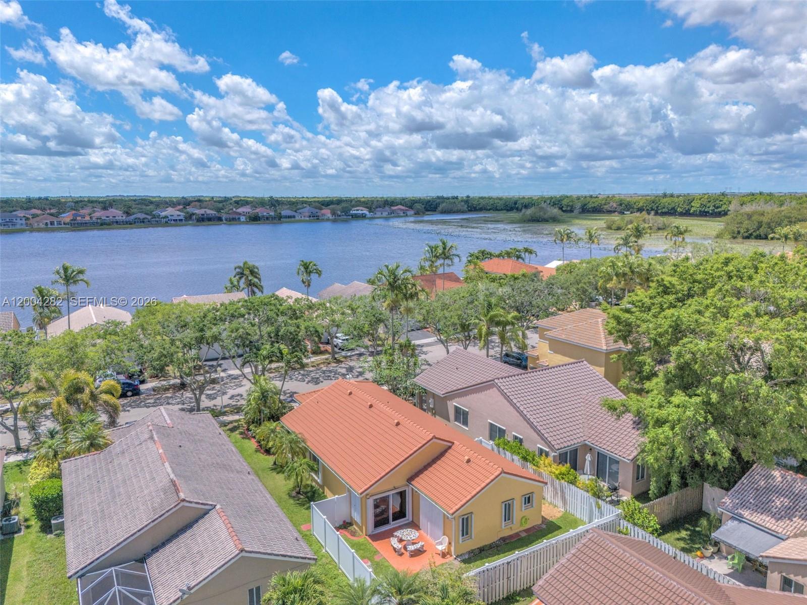 An aerial view shows suburban houses with tile roofs near a large lake — 1600 Salerno Cir, Weston FL 33327, WESTON, FL