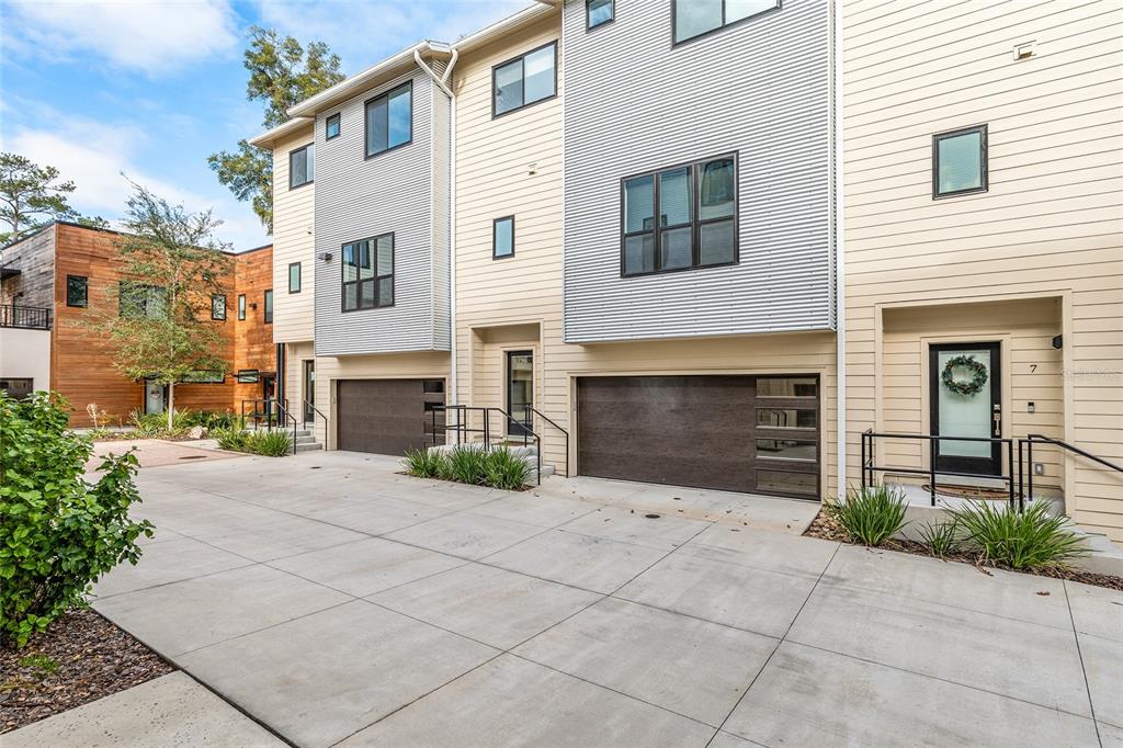 The exterior of modern townhomes features corrugated metal siding, light-colored horizontal panels, and concrete driveways — 2601 SW WILLISTON ROAD UNIT 106, GAINESVILLE, FL