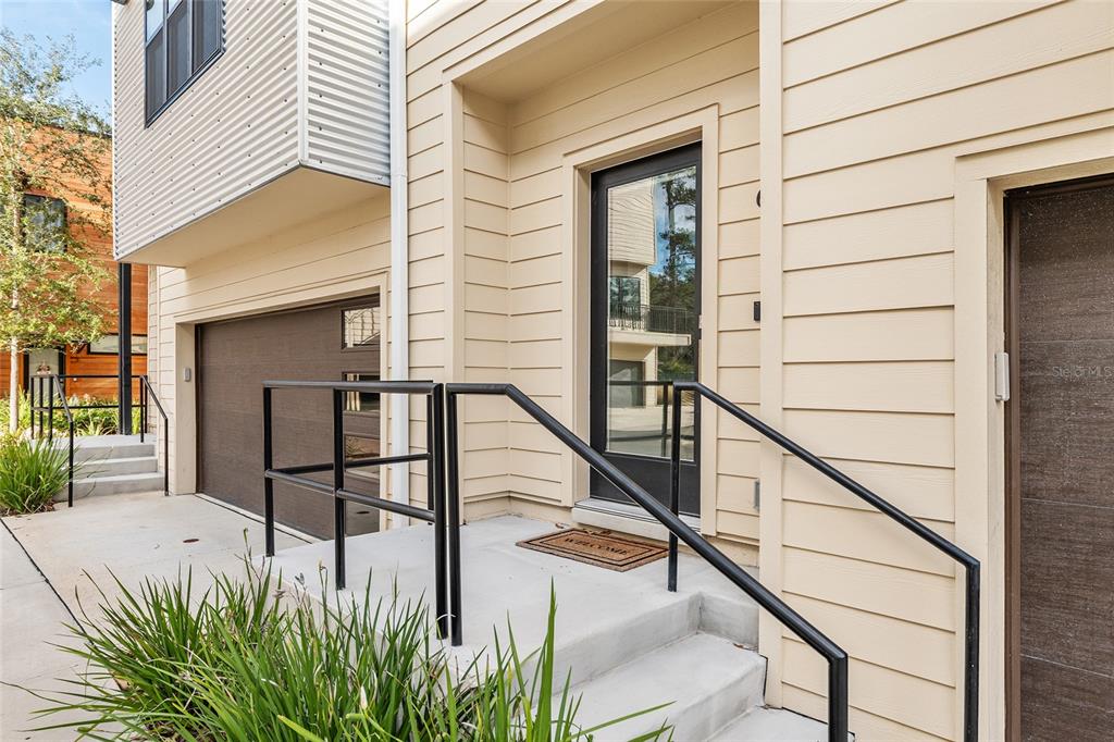 The exterior of a modern home features a beige facade, a front door, and a garage — 2601 SW WILLISTON ROAD UNIT 106, GAINESVILLE, FL