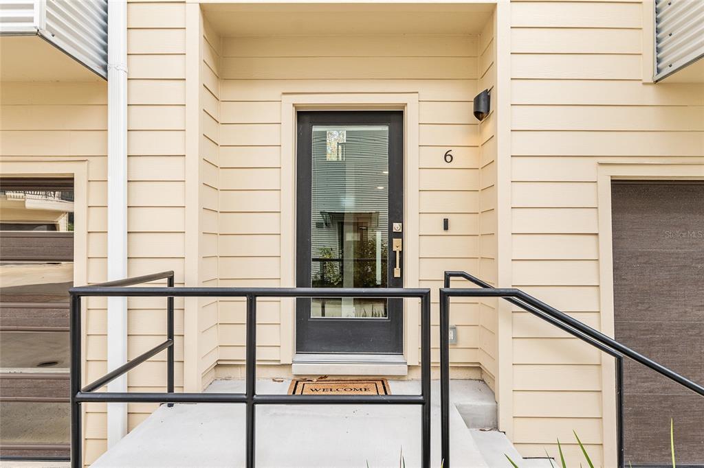 The exterior entrance features a black glass door, a concrete porch, and metal railings — 2601 SW WILLISTON ROAD UNIT 106, GAINESVILLE, FL