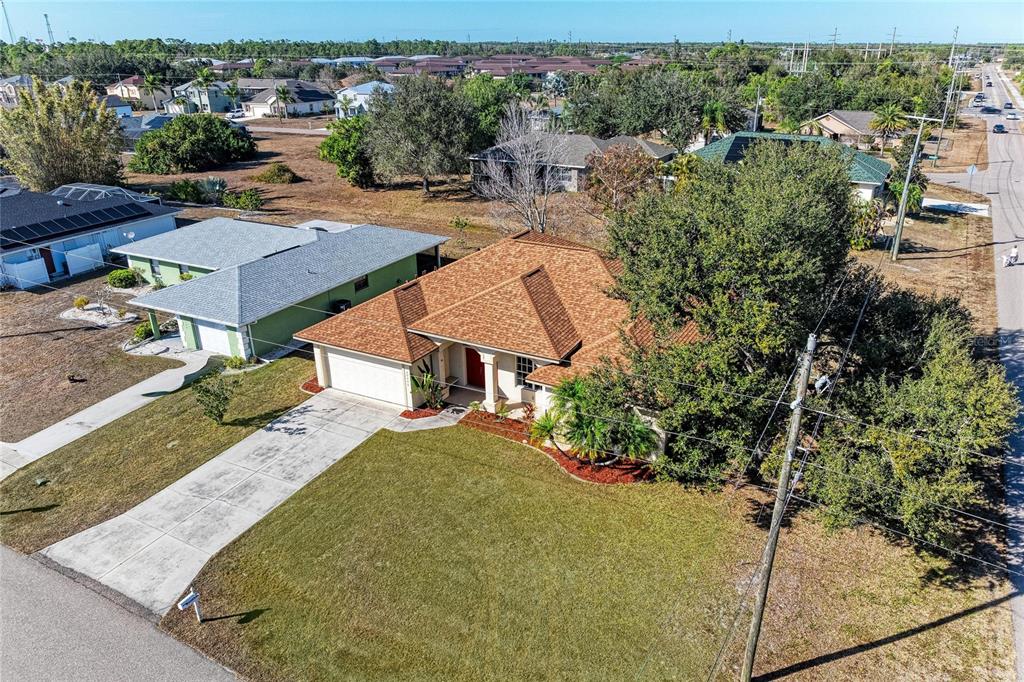 An aerial view shows a single-story house with a brown roof and a front lawn — 25206 NOCTURNE LANE, PUNTA GORDA, FL