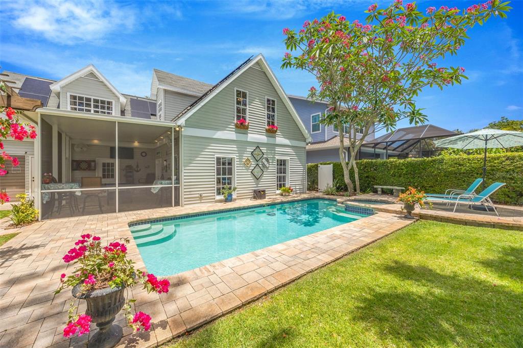 A backyard features a swimming pool, a screened-in patio, and a two-story light gray house — 852 35TH AVENUE N, ST PETERSBURG, FL