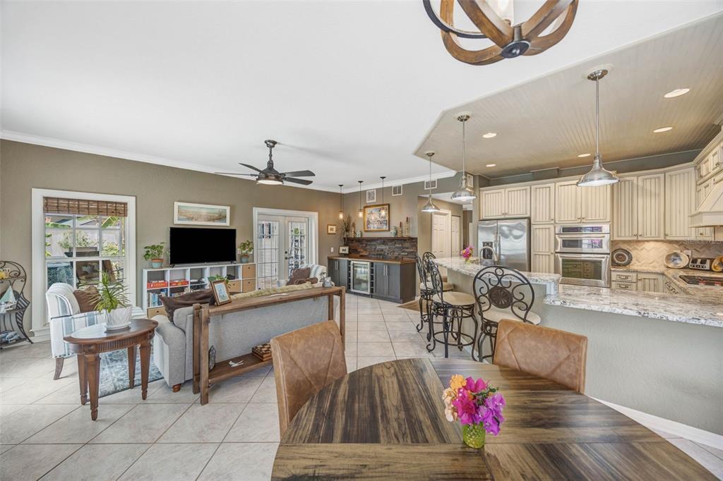 An open-concept kitchen and living area features tile flooring, a breakfast bar, and wood cabinetry — 852 35TH AVENUE N, ST PETERSBURG, FL