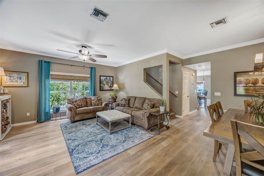 A living room with wood-look flooring, a blue area rug, and brown leather furniture — 852 35TH AVENUE N, ST PETERSBURG, FL