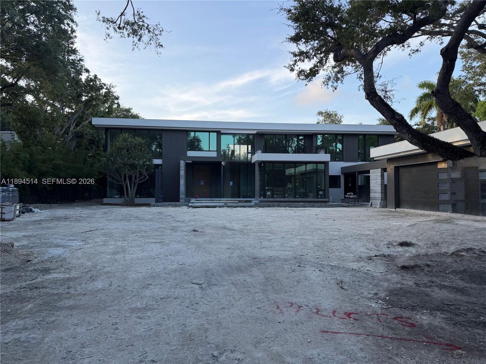 A modern two-story house with large glass windows stands behind an unfinished dirt driveway — 5095 SW 82nd St, Miami FL 33143, MIAMI, FL
