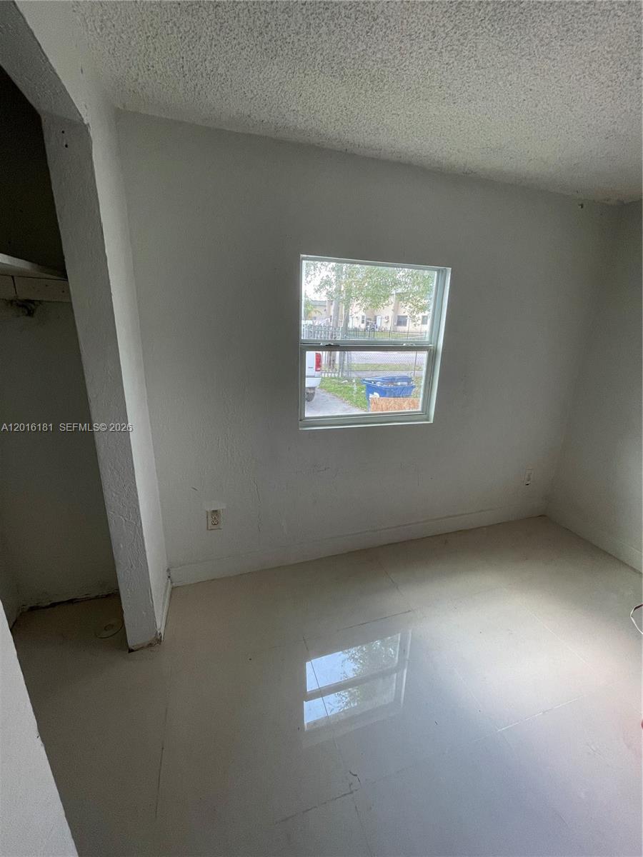 An empty room with white walls, a single window, and light-colored tile flooring — MIAMI, FL