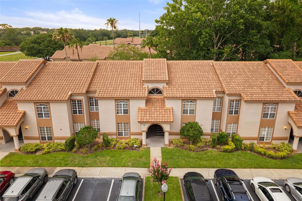 An aerial view of a two-story apartment building with a tiled roof and parking lot — 4690 SUSSEX TERRACE UNIT 103, ORLANDO, FL