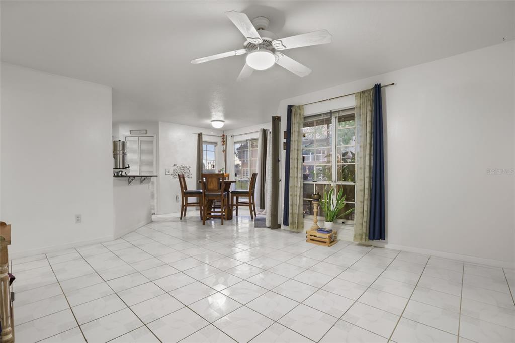 A dining area with white tile floors, a ceiling fan, and a sliding glass door — 4690 SUSSEX TERRACE UNIT 103, ORLANDO, FL
