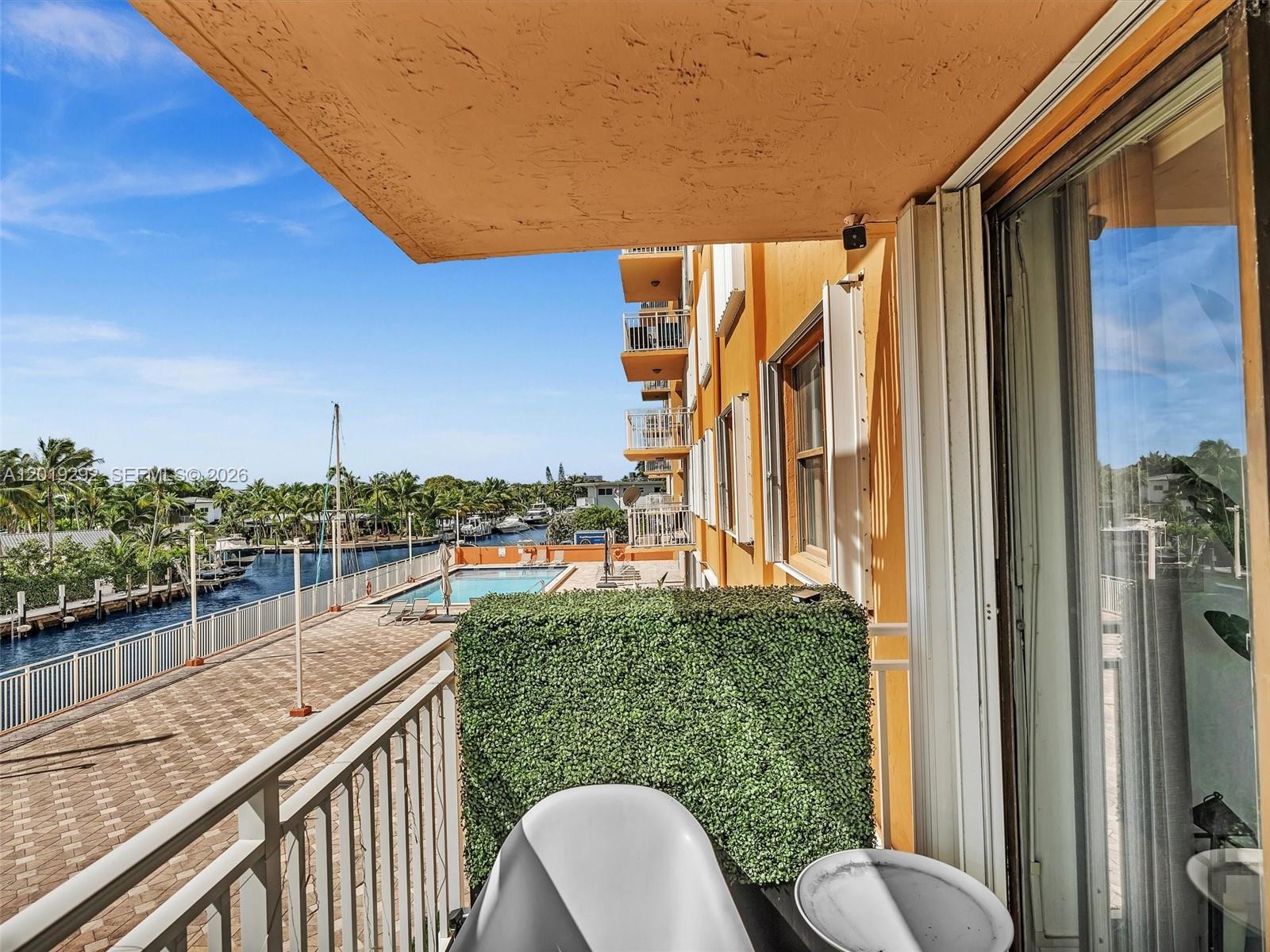 A balcony overlooks a swimming pool, a canal with boats, and a residential landscape — 2450 NE 135th St # 201, North Miami FL 33181, NORTH MIAMI, FL