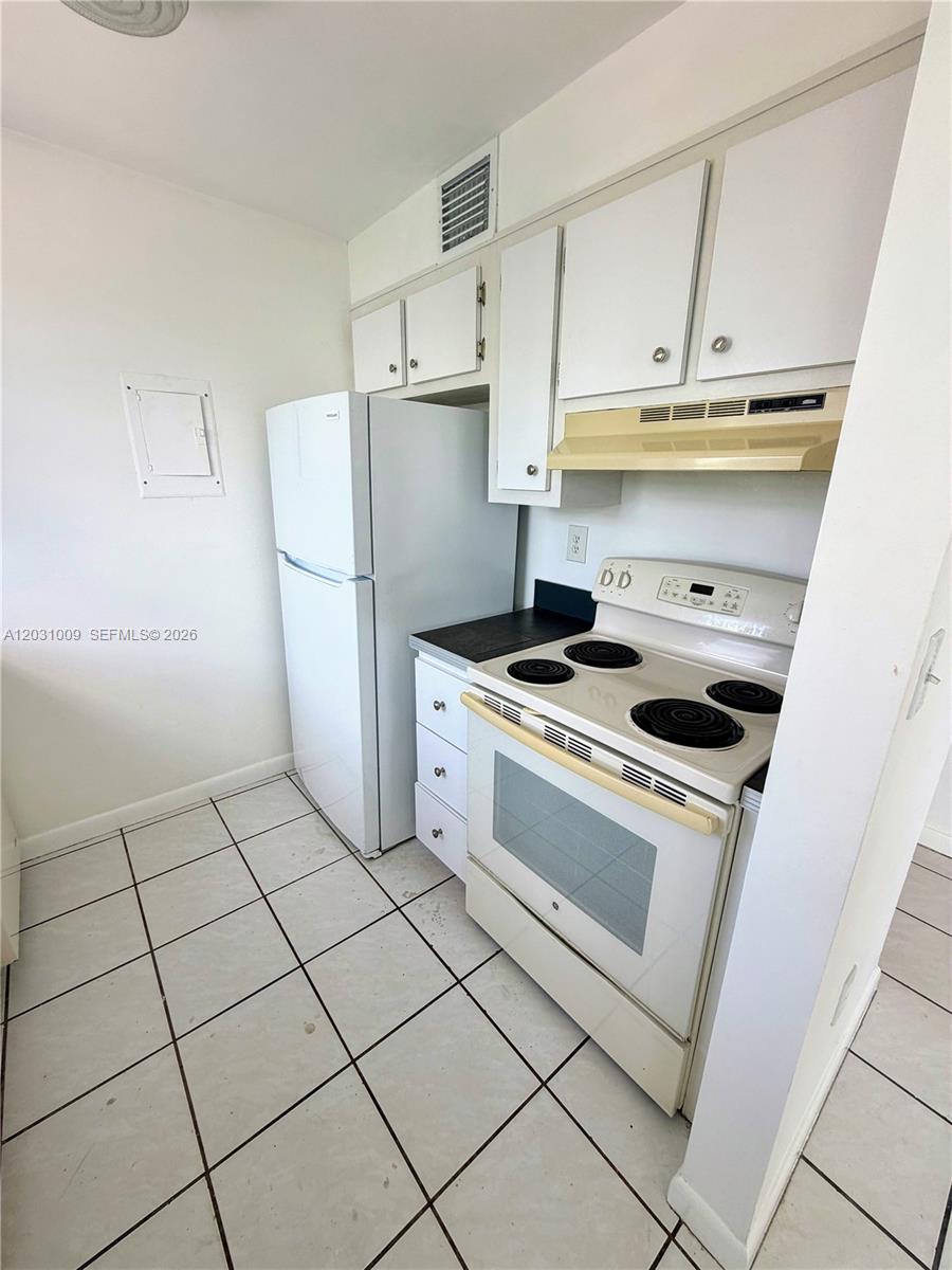 A small kitchen features white cabinets, a white refrigerator, and a white electric stove — 2001 Bay Dr # 401, Miami Beach FL 33141, MIAMI BEACH, FL