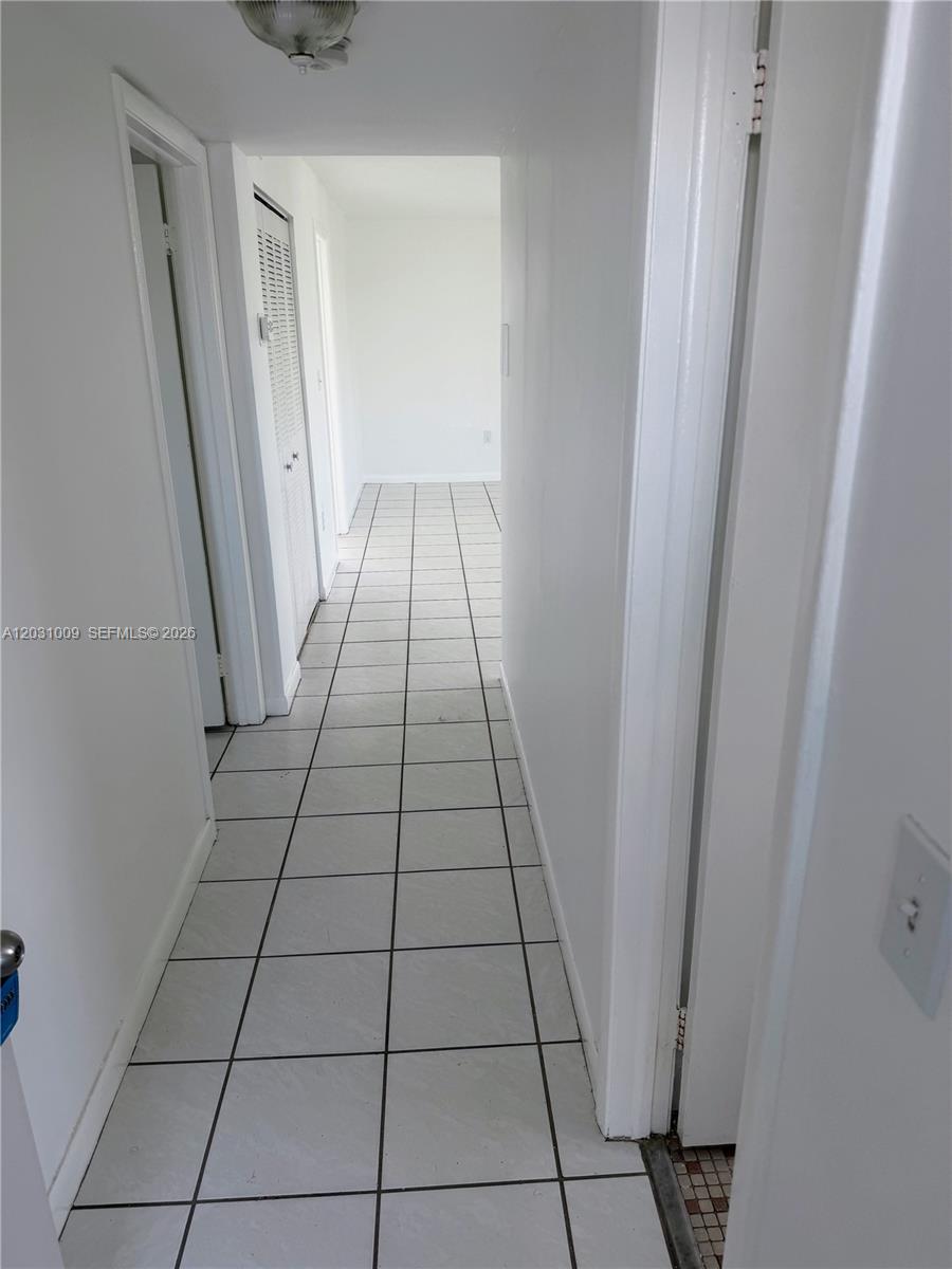 A narrow hallway features white walls, a light fixture, and light-colored square floor tiles — 2001 Bay Dr # 401, Miami Beach FL 33141, MIAMI BEACH, FL