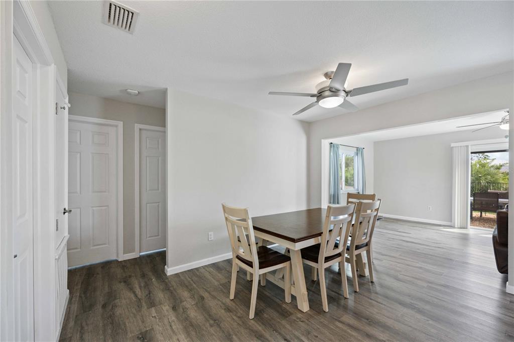 A dining area with a wooden table, chairs, and a ceiling fan on gray flooring — 4394 LIBRARY STREET, PORT CHARLOTTE, FL