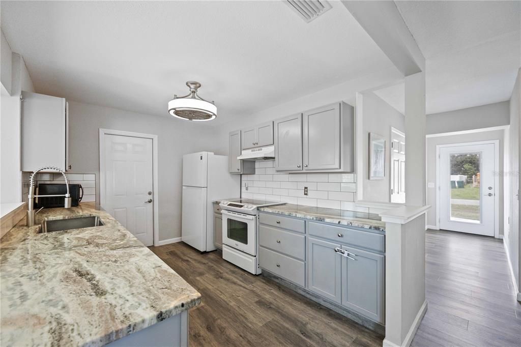 A kitchen features gray cabinets, granite countertops, white appliances, and a white subway tile backsplash — 4394 LIBRARY STREET, PORT CHARLOTTE, FL