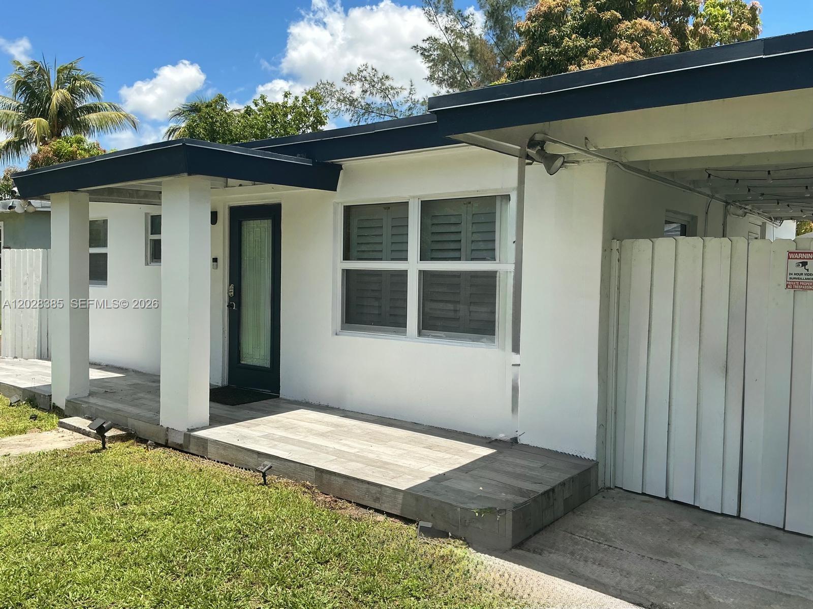 A white single-story house features a tiled front porch, a dark door, and a carport — 6025 SW 40th St, Miramar FL 33023, MIRAMAR, FL