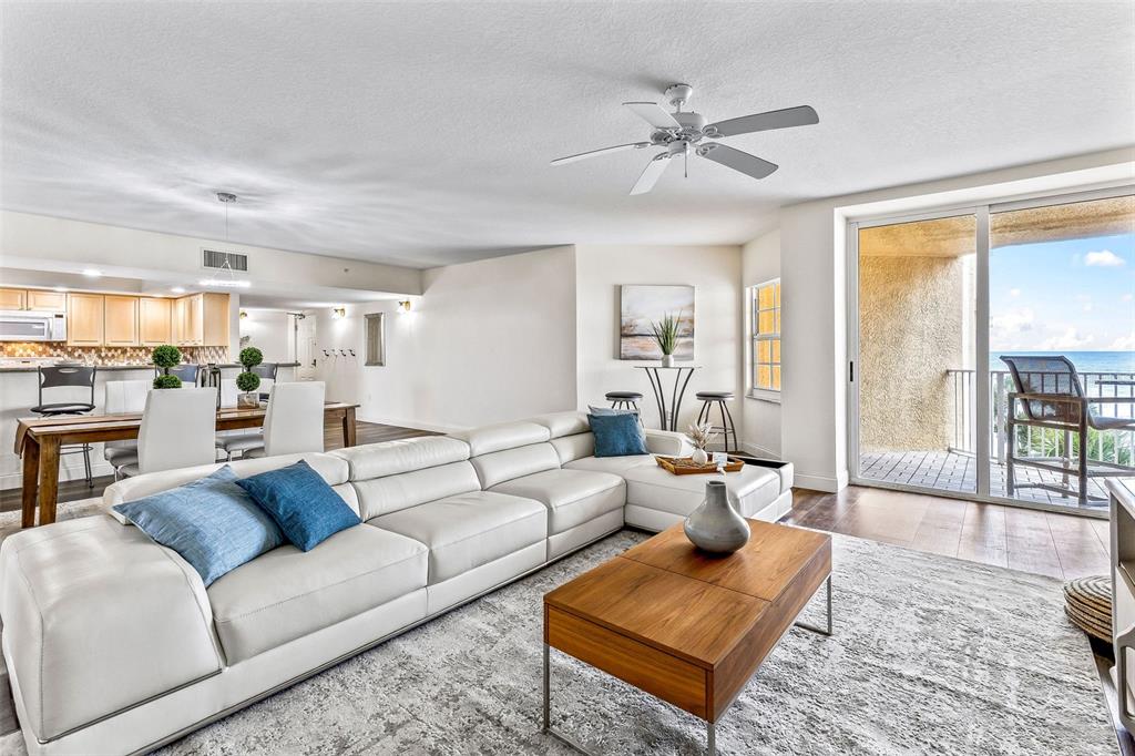 A living room with a white sectional sofa, wooden coffee table, and oceanfront balcony access — 3145 S ATLANTIC AVENUE UNIT 405, DAYTONA BEACH SHORES, FL