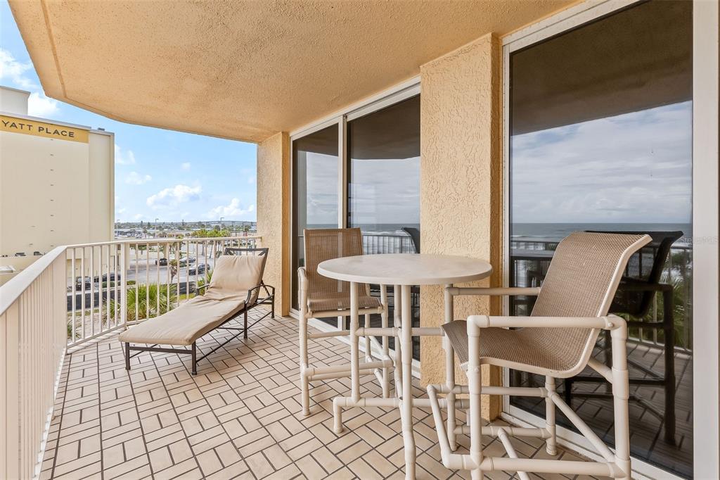 A balcony with tile flooring features a lounge chair, a small table, and two chairs — 3145 S ATLANTIC AVENUE UNIT 405, DAYTONA BEACH SHORES, FL