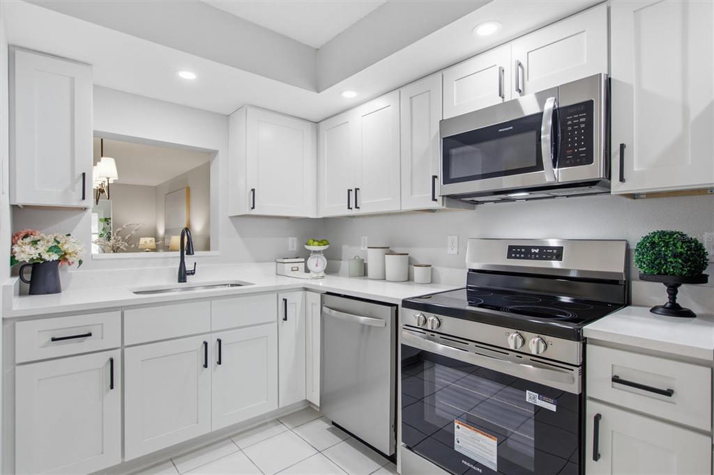 A modern kitchen features white cabinets, stainless steel appliances, and white countertops — 1241 S MARTIN LUTHER KING JR AVENUE UNIT 104, CLEARWATER, FL