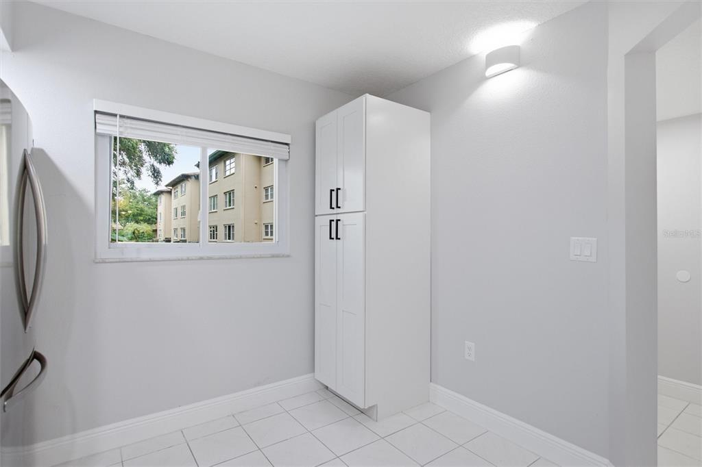 A white kitchen pantry cabinet stands in a room with white tile flooring and windows — 1241 S MARTIN LUTHER KING JR AVENUE UNIT 104, CLEARWATER, FL